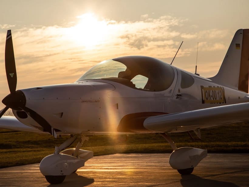 A white Bristell B23 parked on the apron in low evening sun