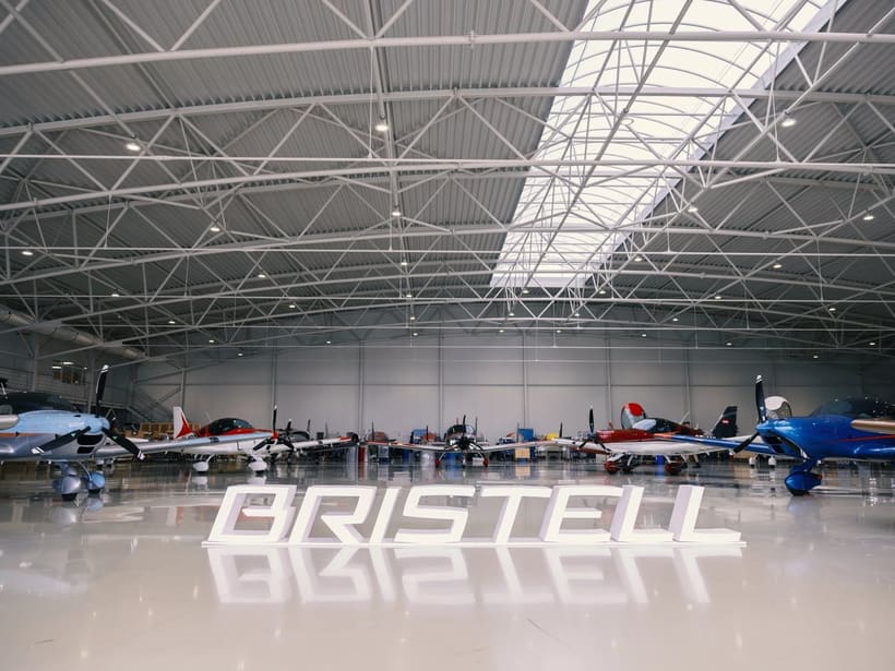 Bristell-Flugzeuge aufgereiht in der Halle in Kunovice, mit einem großen Bristell-Schriftzug auf dem Boden, 2026