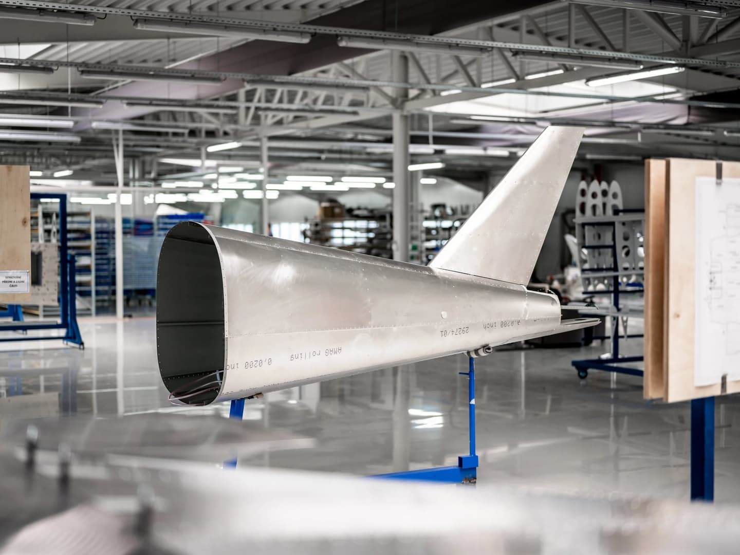 A bare aluminium rear fuselage section with its vertical stabiliser, on a stand on the Bristell factory floor